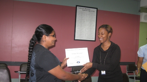 ABE Business Management Level 4 student, Ms. Farnaaz Mohammed, smiles as she accepts her certificate from Senior Academic Administrator, Ms. Patrice Belfon